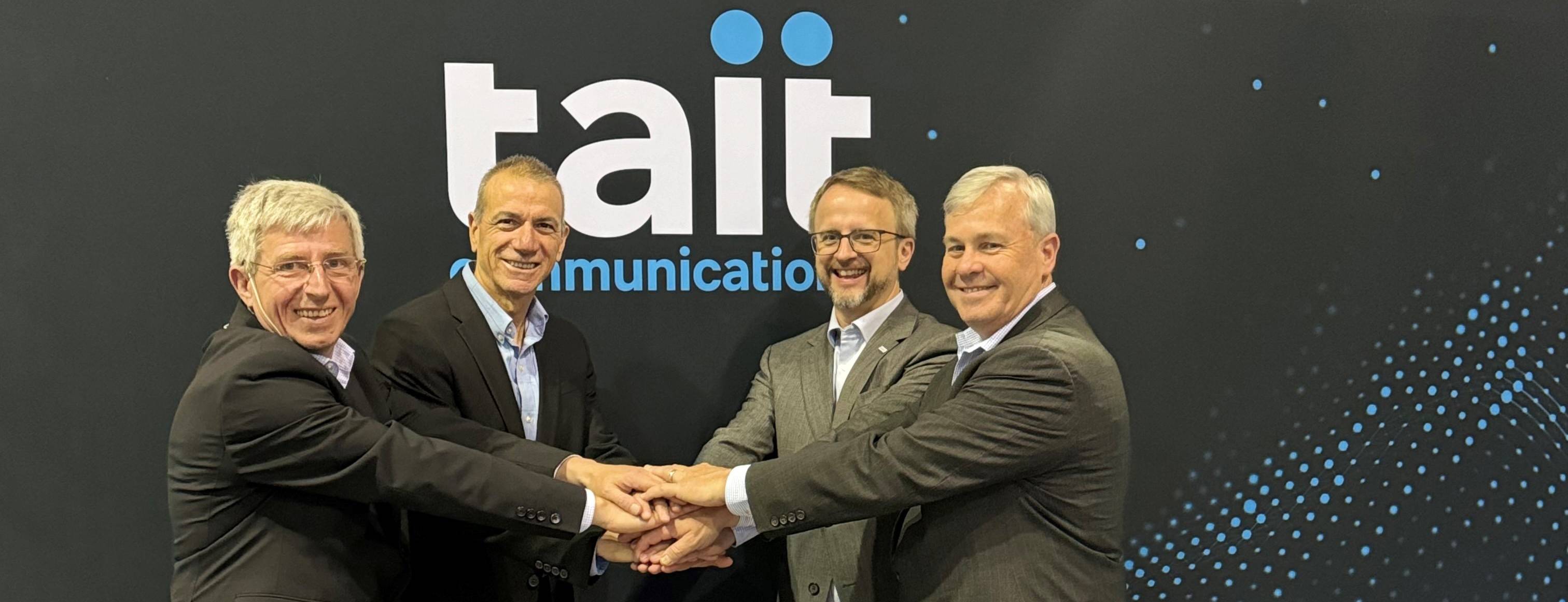 Four men from Frequentis and Tait shake hands