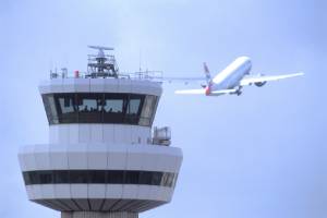 an ascending airplane behind Gatwick tower