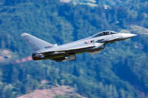 ein startendes Militär-Flugzeug; im Hintergrund Wald