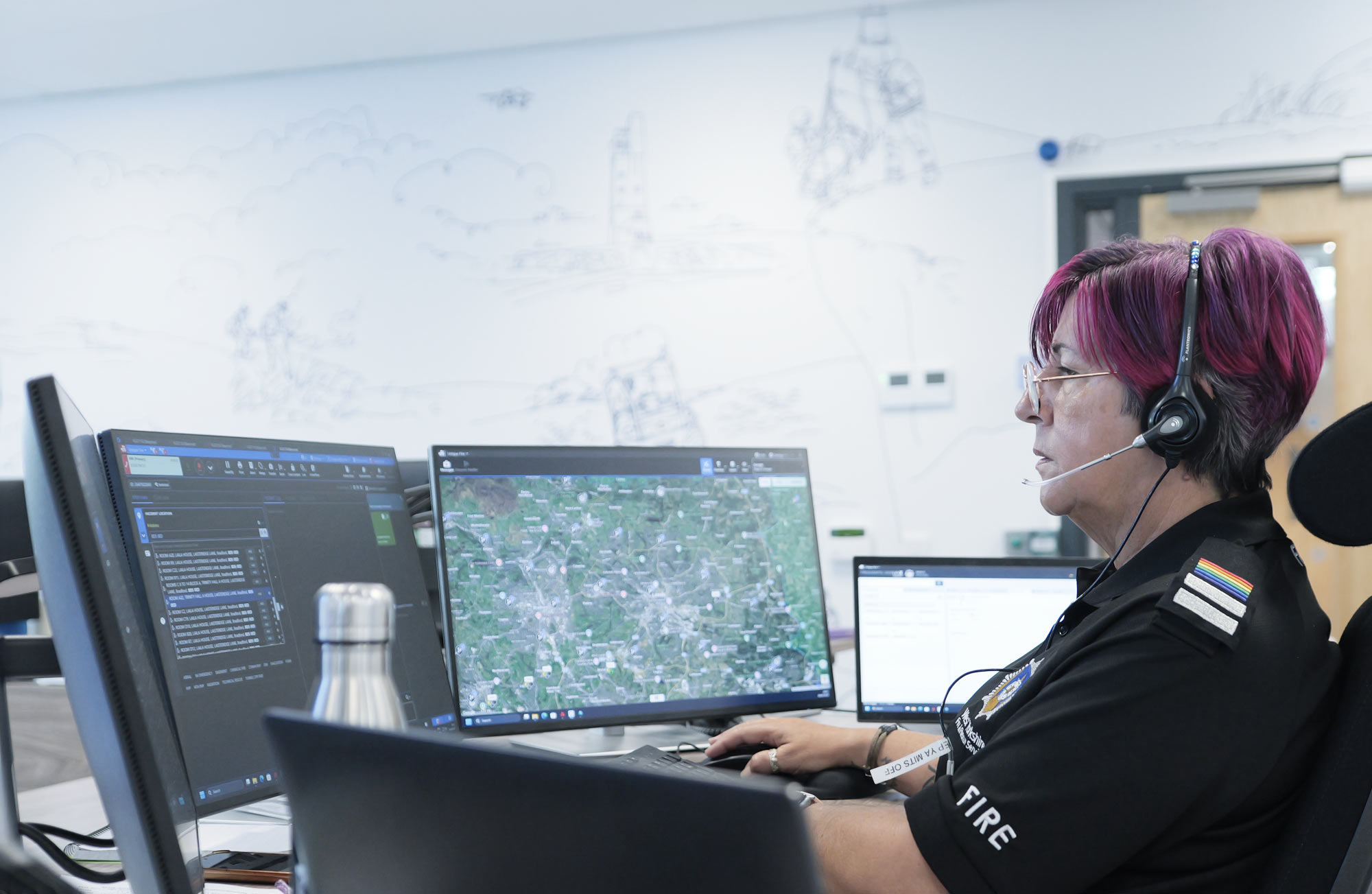 Unique CAD Suite header picture, showing a woman in a public safety control room, and four screens in front of her