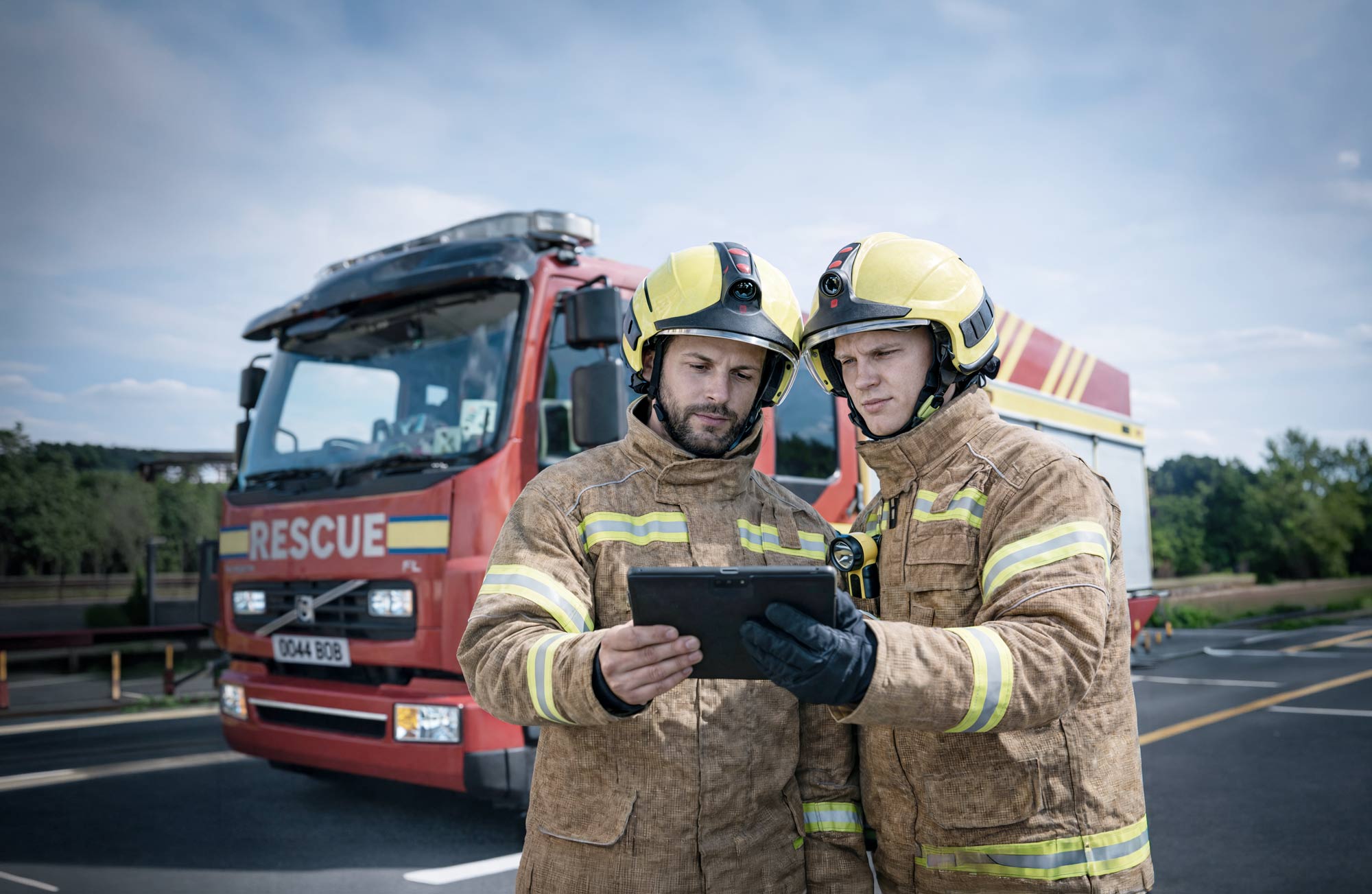 OnSite header picture, showing two firefighters, an operating device, and a rescue vehicle in the background