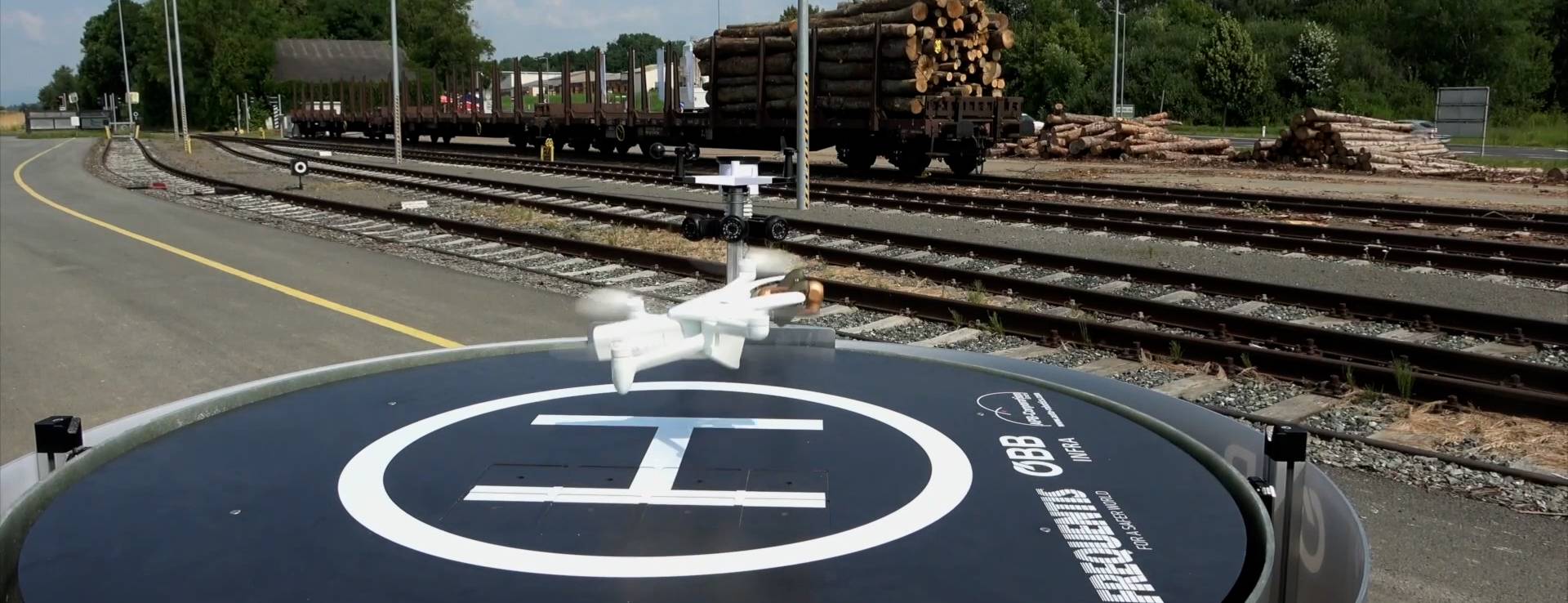 Drone leaving drone hangar beside rail tracks