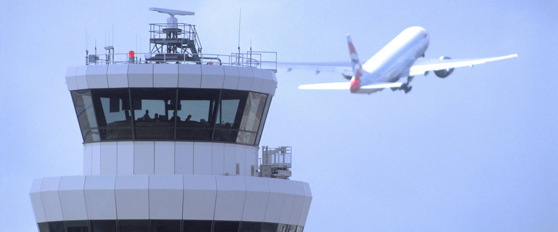 an ascending airplane behind Gatwick tower