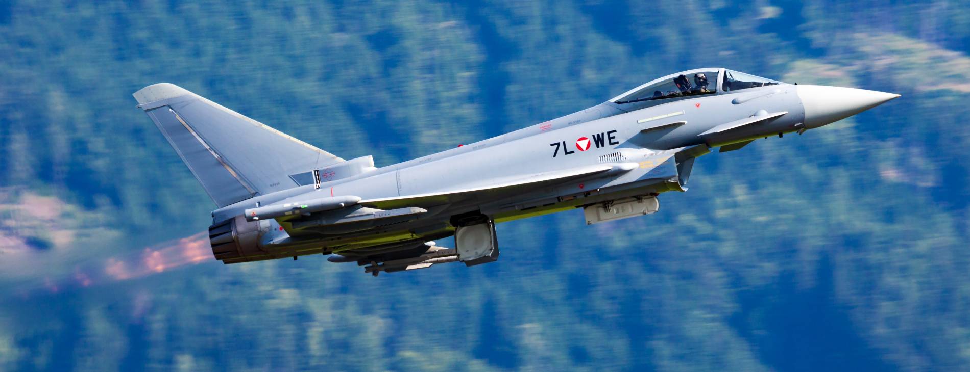 ein startendes Militär-Flugzeug; im Hintergrund Wald