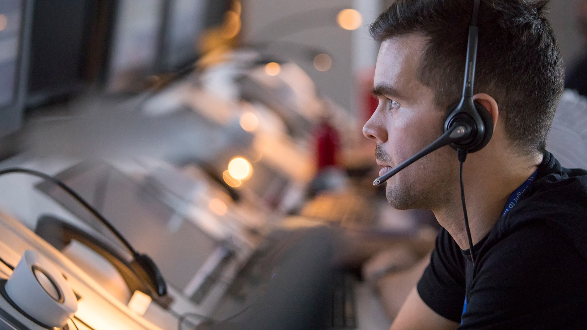 male controller with headset in front of screens